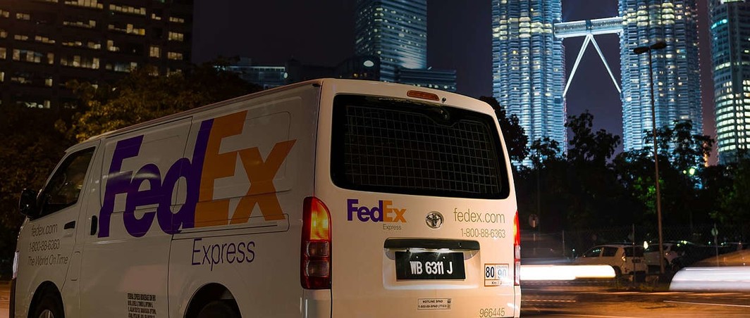 Delivery van of express shipping carrier FedEx in Kuala Lumpur, the capital of Malaysia, with the Petronas Twin Towers in the background